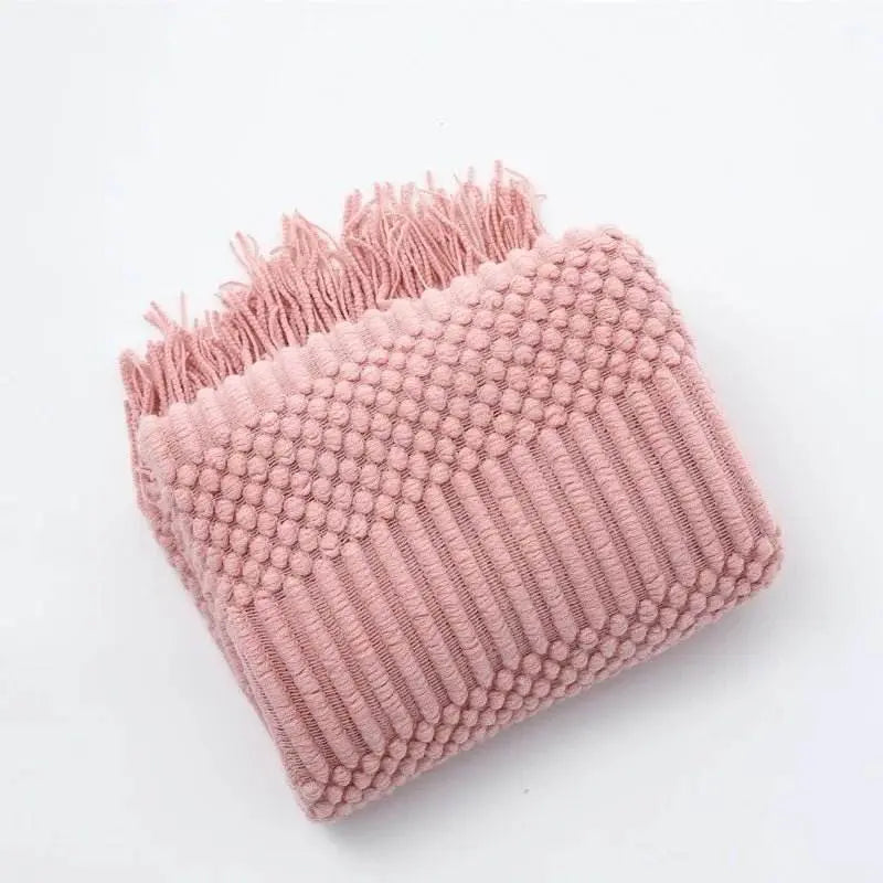Knitted soft throw blanket with tassels in pink, featuring an intricate woven texture and cozy acrylic fabric.