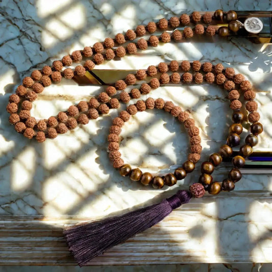 Hand-knotted Rudraksha and Tiger Eye mala bracelet set on marble; 108 beads for meditation, spirituality, and protection.