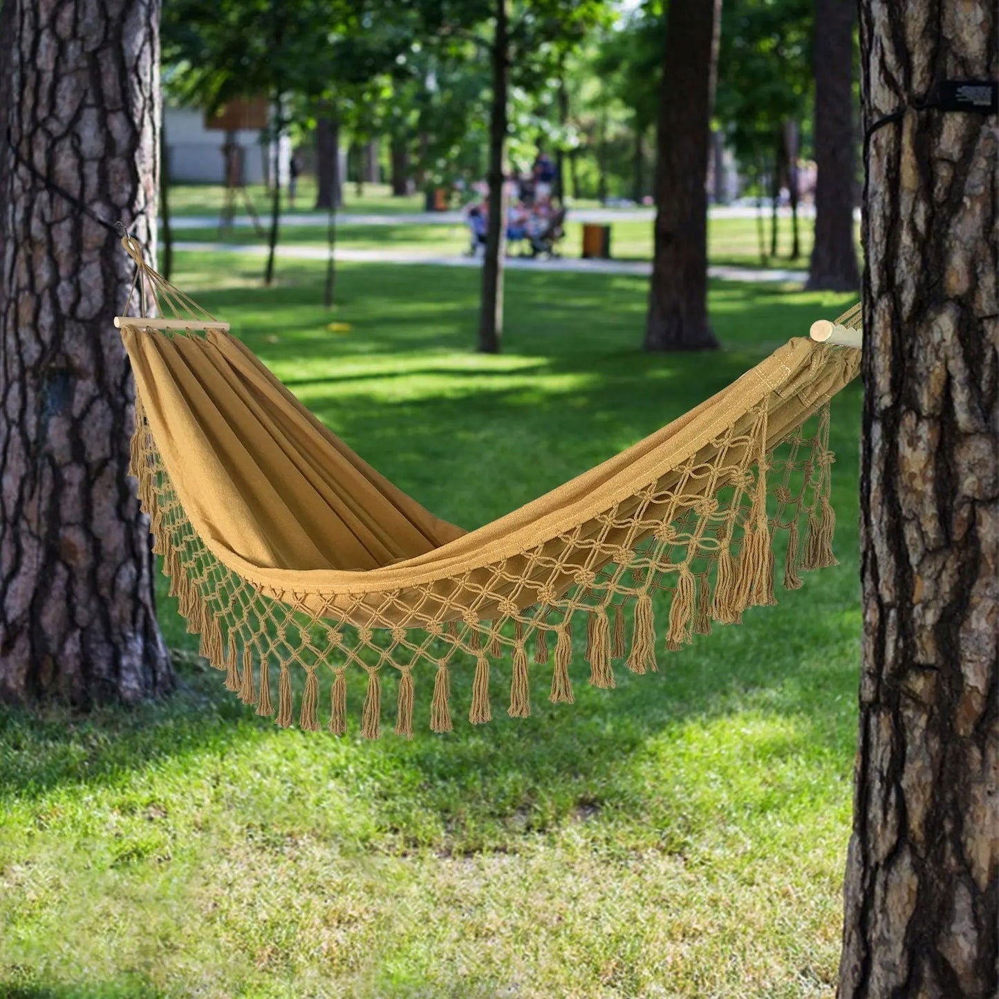 Gold, turquoise, and grey double hammock with macramé, wood bars, and stylish tassels in a serene outdoor setting.