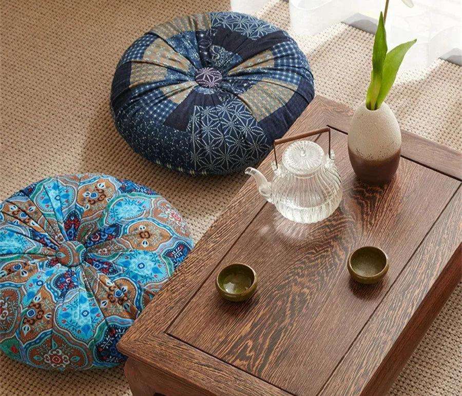 Handmade Boho round thick floor cushions with vibrant designs next to a wooden tea table.